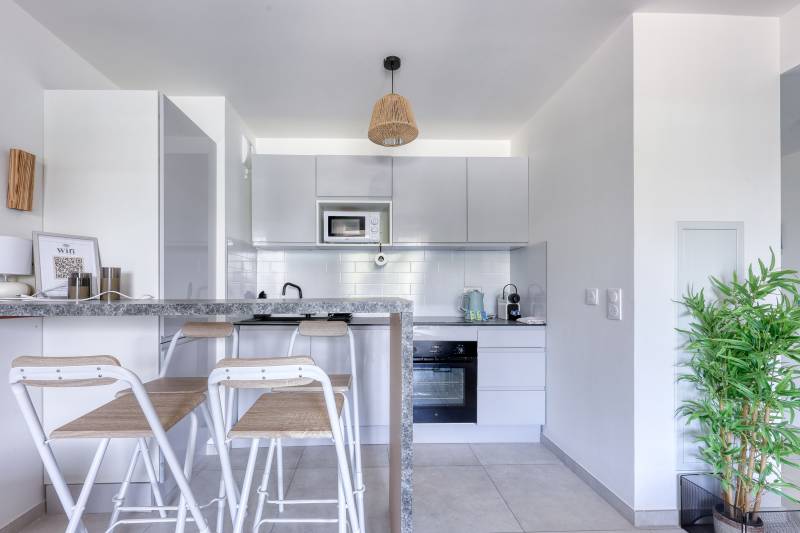 Cuisine blanche entièrement équipée avec coin repas et bar – Location saisonnière haut de gamme à Cannes, Alpes-Maritimes